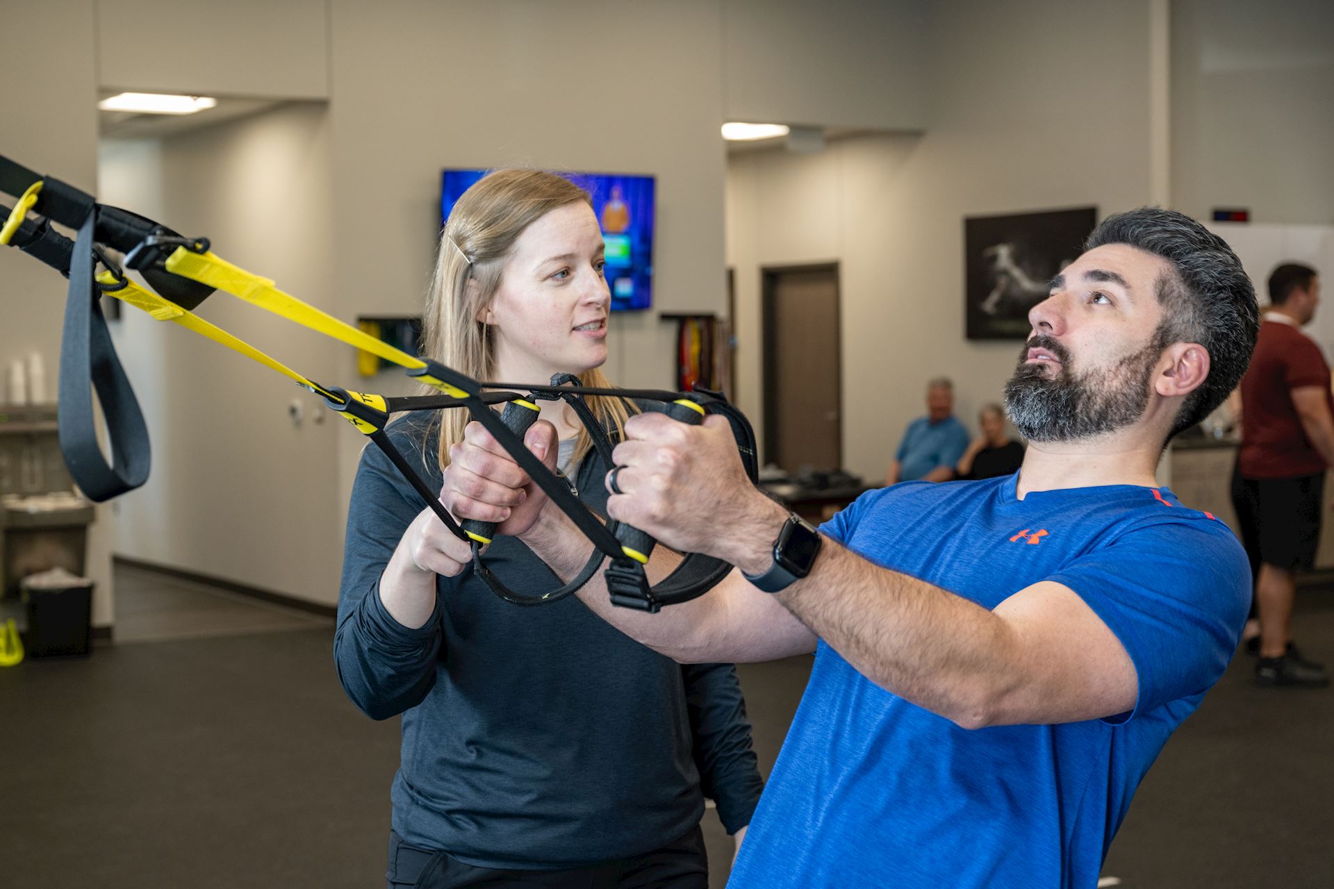 physical therapist assisting patient with proper use of a suspension training system